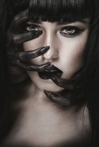 Woman with black demon hands on face