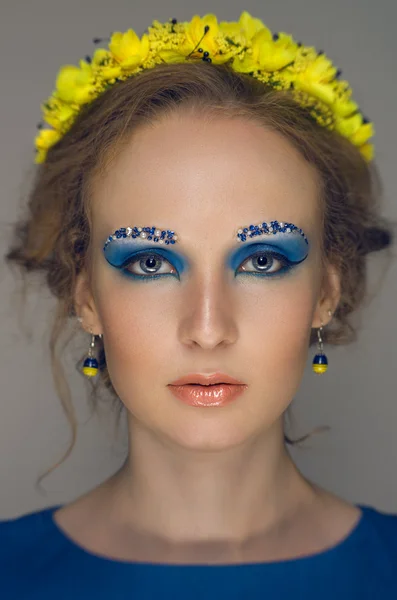 Vrouw met blauwe make-up in gele krans — Stockfoto