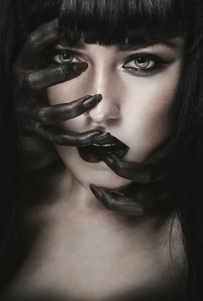 Frau mit schwarzen Dämonenhänden im Gesicht Stockbild
