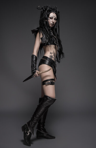 Young sexy woman warrior in black costume holding sword in hands
