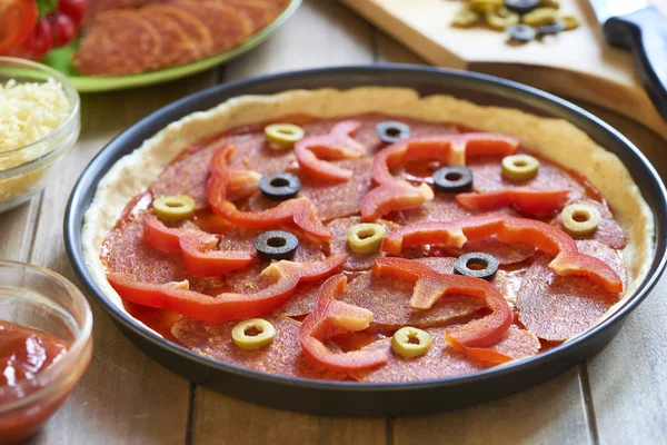 Pizza caseira com pepperoni, pimenta e azeitonas. Processo de cozedura. Passo 5. Exponha ingredientes na massa de farinha Imagens De Bancos De Imagens