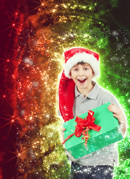 Happy boy in santa hat surprised by christmas present — Stok fotoğraf