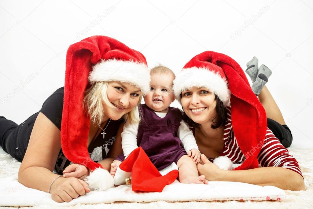 smiling infant baby with two womans with santa hats