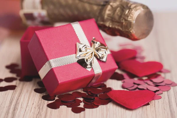 Bottle of vine, red hearts and small present — Stock Photo, Image