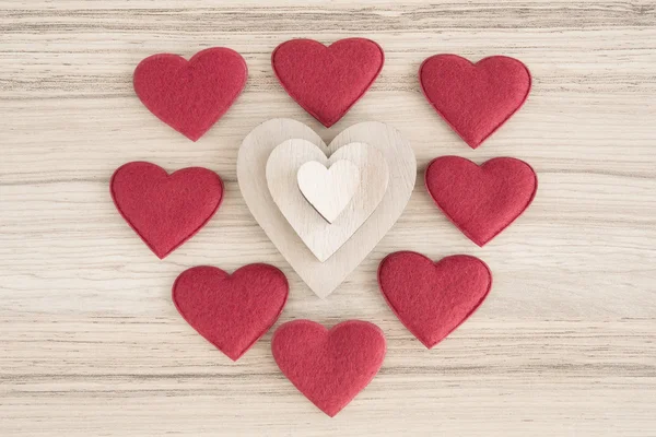 Valentijnsdag weefsel en houten harten op een houten achtergrond — Stockfoto