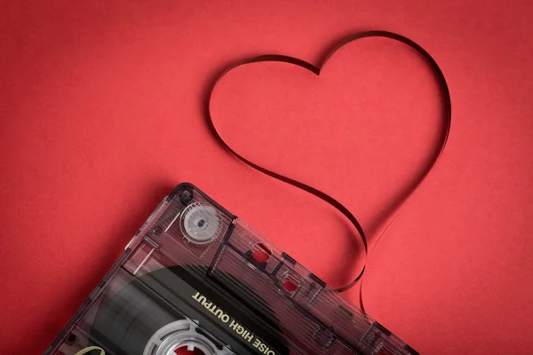Zvuková kazeta pásek na červené pozadí. Film, tvarování srdce — Stock fotografie