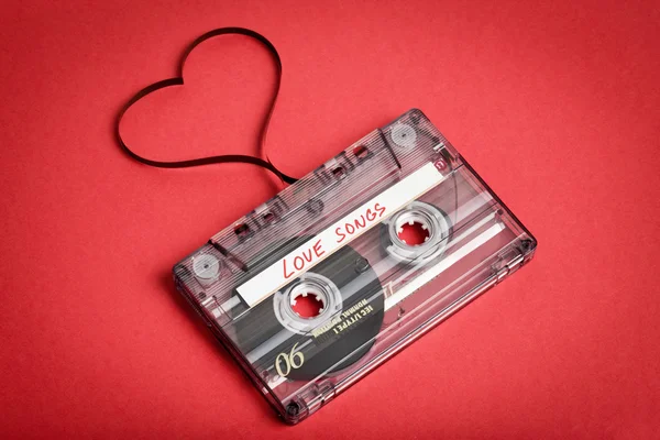 Audio cassette tape on red backgound. Film shaping heart — Stock Photo, Image