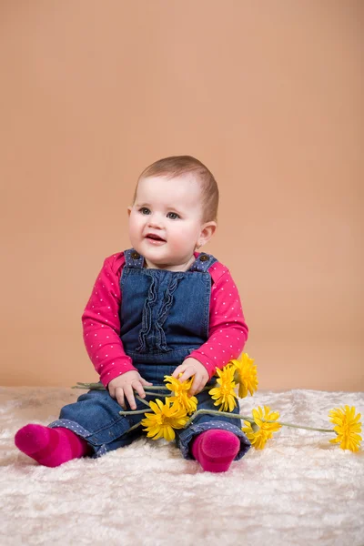 Smiling infant baby with yellow flowers — Stock Photo, Image