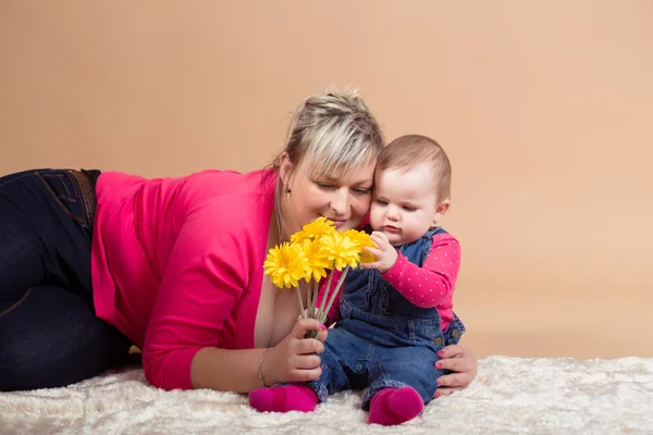 Säugling mit seiner Mutter und gelben Blumen — Stockfoto