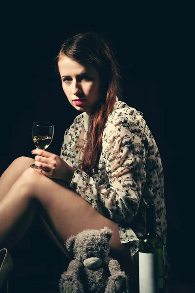 Beautiful young brunette woman holding a bottle of white wine — Stock Photo, Image