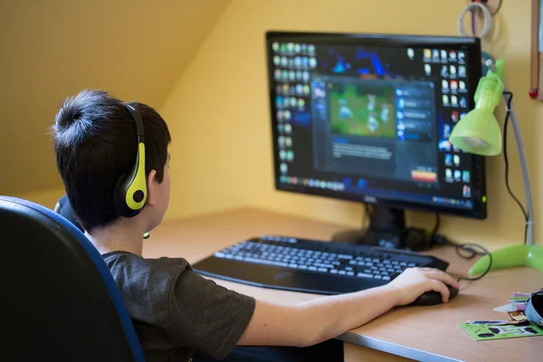 Niño usando la computadora en casa, jugando juego Imagen de archivo