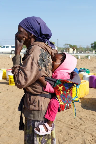 Pequena criança namibiana nas costas de sua mãe — Fotografia de Stock