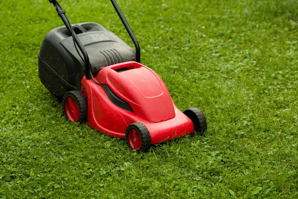 Red lawnmower on green grass — Stock Photo, Image