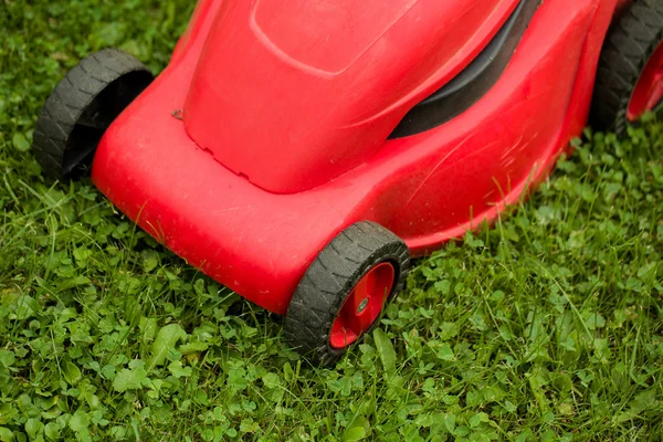 Червона газонокосарка на зеленій траві — стокове фото