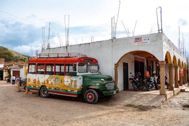 Villa de Leyva, Boyaca, Colombia - November 19 2023: A traditional, brightly painted chiva bus is parked by a historical whitewashed building in Villa de Leyva.