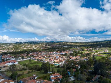 Expansive aerial view of Villa de Leyva well-preserved colonial cityscape, featuring whitewashed buildings and red tiled roofs set against the Boyaca landscape. Villa de Leyva, Boyaca, Colombia