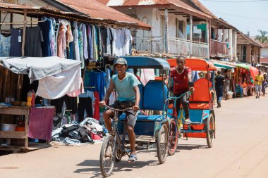 Miandrivazo, Madagascar - October 11 2025: Daily commute in Miandrivazo, showing the brightly covered cycle rickshaws used for passenger transport.