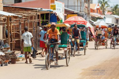 Miandrivazo, Madagascar - October 11 2025: Daily commute in Miandrivazo, showing the brightly covered cycle rickshaws used for passenger transport.