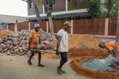 Morondava, Madagascar - November 3 2022: Local men carrying large stones for construction, demonstrating manual labor in the Nosy Kely area of Morondava.