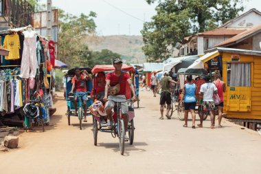 Miandrivazo, Madagascar - October 11 2025: Daily commute in Miandrivazo, showing the brightly covered cycle rickshaws used for passenger transport.