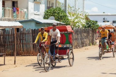Miandrivazo, Madagascar - October 11 2025: Daily commute in Miandrivazo, showing the brightly covered cycle rickshaws used for passenger transport.