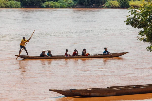 Miandrivazo, Madagascar - October 11 2025: Local Malagasy people traveling by traditional pirogue on the red-brown river near Miandrivazo, Menabe.