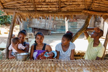 Brickaville, Toamasina Eyaleti, Madagaskar - 17 Ekim 2016: Bir grup kadın, çocuk ve bir genç Brickaville köyündeki sazdan çatı altında toplandı.