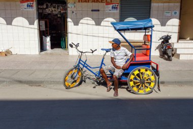 Toamasina, Madagaskar - 17 Ekim 2016: Yerel bir taksi şoförü, Tamatave 'deki küçük bir dükkanın önünde, yaygın bir ulaşım biçimi olan siklosu üzerinde dinleniyor.