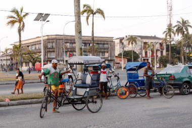 Toamasina, Madagaskar - 17 Ekim 2016: Yerel halk, liman kentinde popüler bir toplu taşıma biçimi olan merkez meydanı yakınlarındaki siklosuz triportörlerinin yanında duruyor.