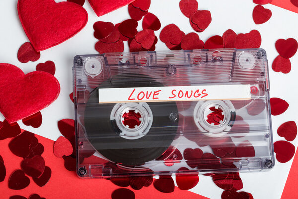 Audio cassette tape on red background with fabric heart