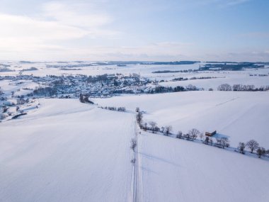 Çek İskoçya 'sında karla kaplı kırsal bir arazinin tepeden görünüşü, bir yol, çıplak ağaçlar ve parlak, güneşli bir gökyüzü altında geniş alanlar. İskoçya, Vysocina, Çek Cumhuriyeti