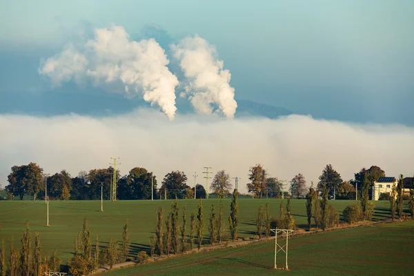 Smoking chimneys in from factory hidden in mist — Stock Photo, Image
