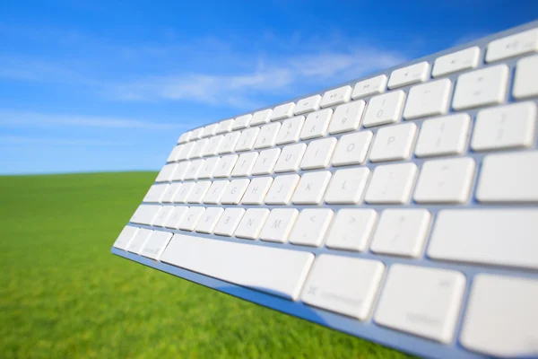 Teclado do computador no céu e grama fundo — Fotografia de Stock