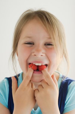 The smiling girl with raspberries in her mouth