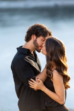 Gün batımında deniz kenarında öpüşen romantik çift.