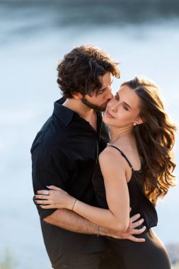 Gün batımında sahilde kucaklaşan romantik çift.