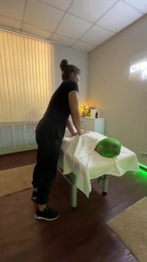 Masaj terapisti seanstan önce çalışma alanını yeşil ışıklandırmalı rahat stüdyoda hazırlıyor.