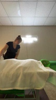 Masaj terapisti stüdyoda vücut masajı sırasında ritmik hareketlerle çalışıyor.