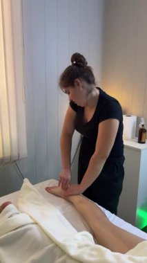 Modern kaplıca odasında kadın terapist tarafından yapılan profesyonel bacak ve ayak masajı, vücut iyileşmesi için rahatlama terapisi