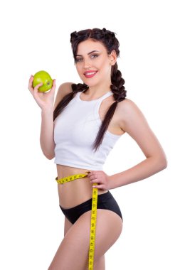 Gülümseyen atletik kadın yeşil elma tutuyor ve beyaz arka planda izole edilmiş belini ölçüyor.