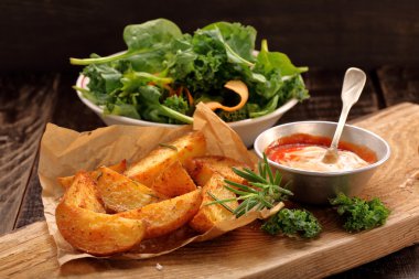 Kavrulmuş patates sosu ve ahşap masa üzerinde taze salata ile