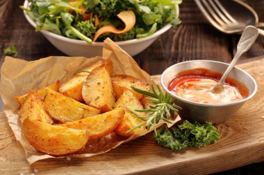 Kavrulmuş patates sosu ve ahşap masa üzerinde taze salata ile