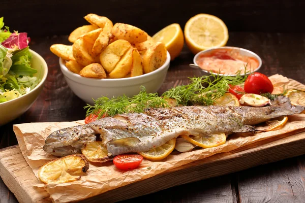 Ugnsbakad fisk med rostad potatis och sallad Royaltyfria Stockfoton