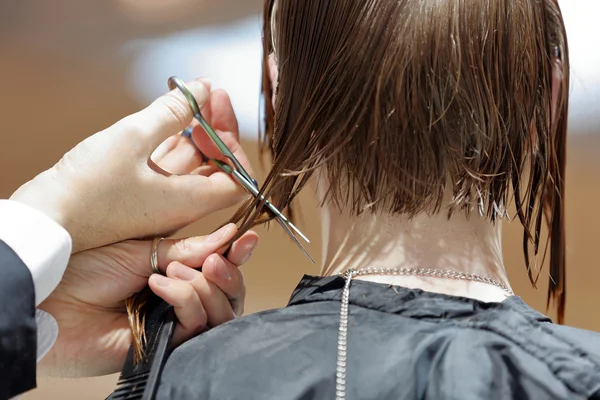 Fryzjer przycinanie brązowe włosy nożyczkami — Zdjęcie stockowe