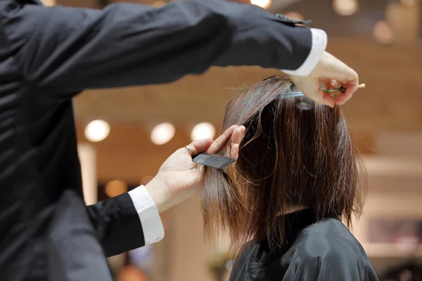 Cabeleireiro aparar cabelos castanhos com tesoura — Fotografia de Stock