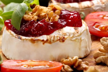 Grilled brie cheese with cranberry jam and walnuts on old wooden clipart