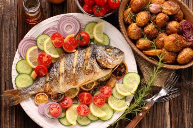 Kavrulmuş patates ve sebze plaka üzerinde ızgara balık