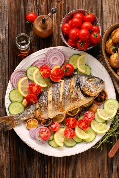Ikan panggang dengan kentang panggang dan sayuran di piring — Stok Foto