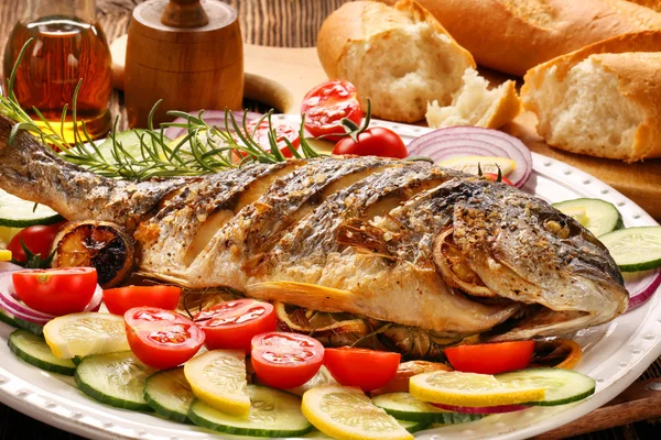 Grilled fish with baguette and vegetables on the plate — Stock Photo, Image