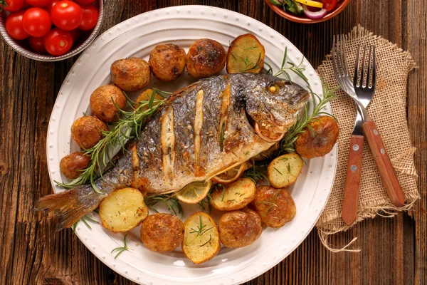 Pesce alla griglia con patate arrosto e verdure sul piatto — Foto Stock